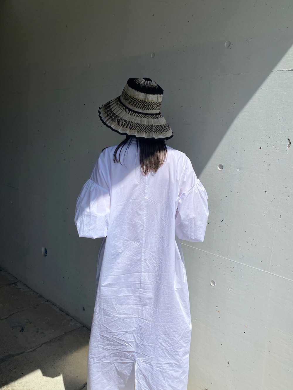 ブラック系のその他シューズ、ホワイト系のワンピース、ブラック系のハットを着用したレディースの夏コーディネートの5枚目の写真