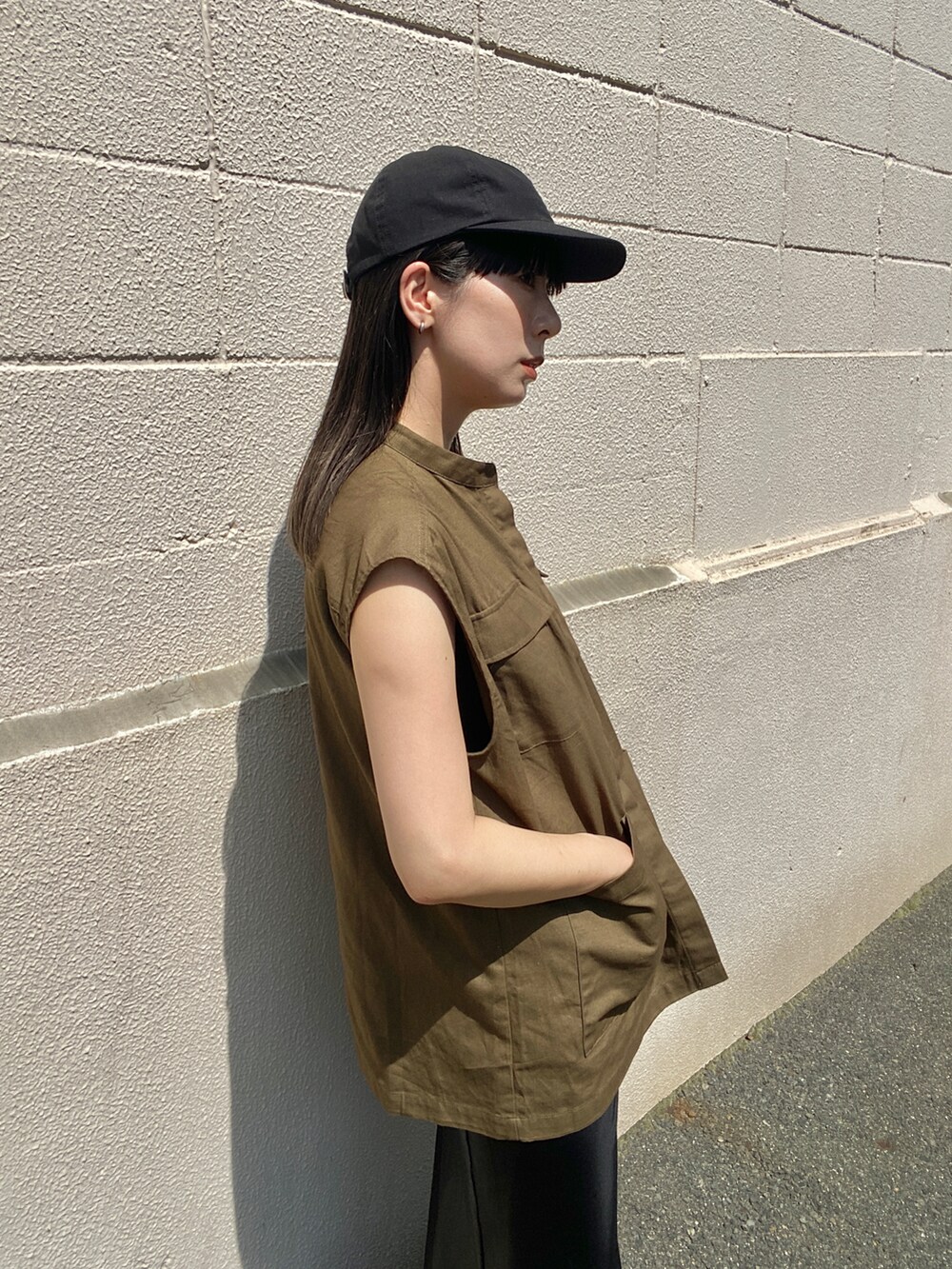 グリーン系のベスト、ブラック系のスカート、ブラック系のサンダルを着用したレディースの夏コーディネートの5枚目の写真