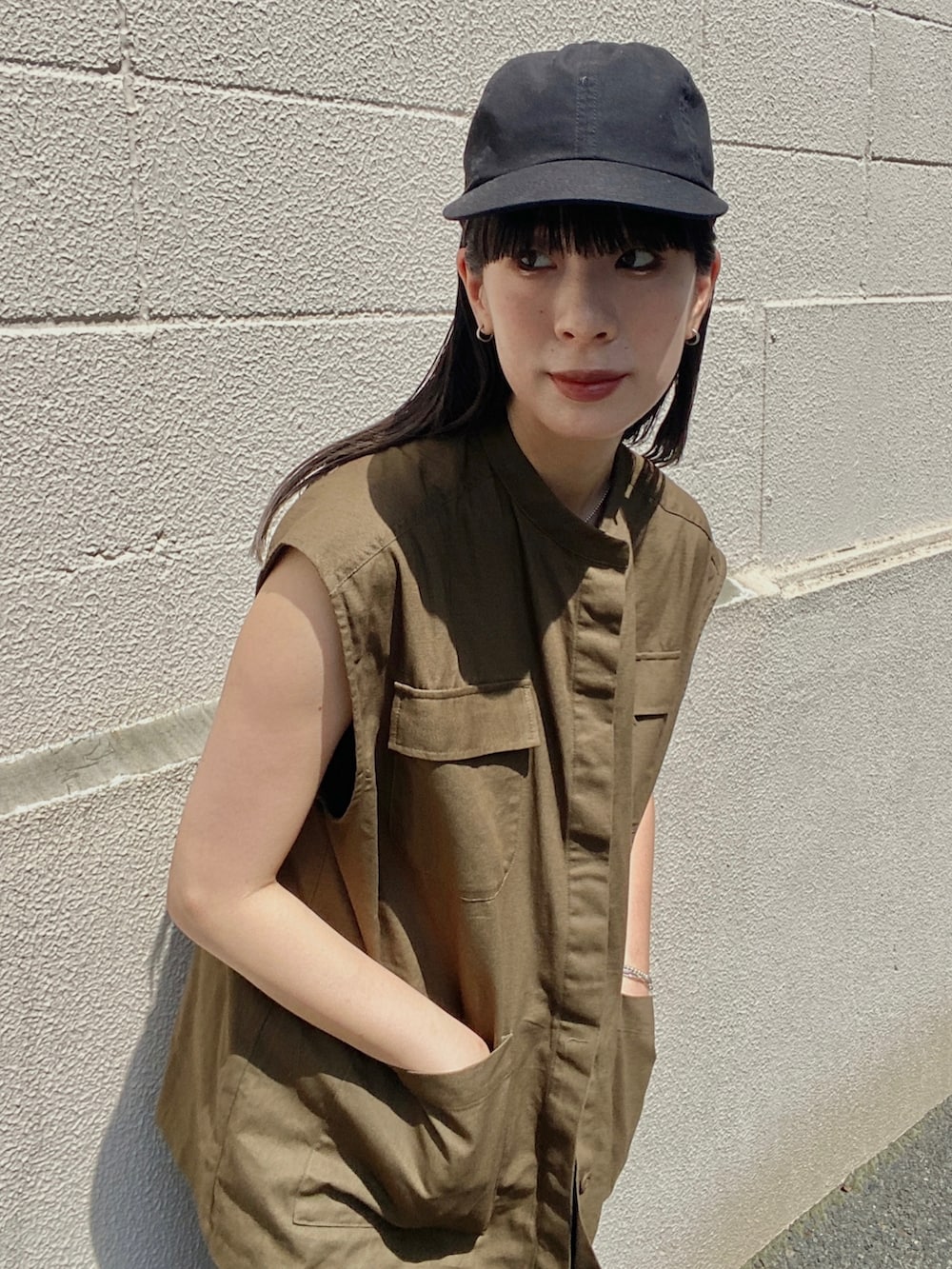 グリーン系のベスト、ブラック系のスカート、ブラック系のサンダルを着用したレディースの夏コーディネートの4枚目の写真