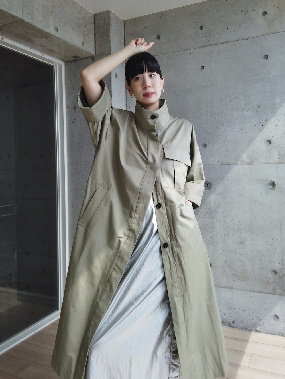 シルバー系のスカート、グリーン系のトレンチコート、ブラック系のシューズを着用したレディースの春コーディネートの3枚目の写真