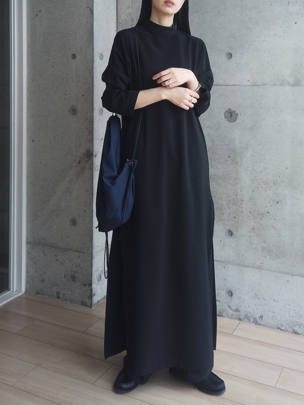 ブラック系のワンピース、ブラック系のモカシン/デッキシューズ、ブルー系のバックパック/リュックを着用したレディースの春コーディネートの4枚目の写真