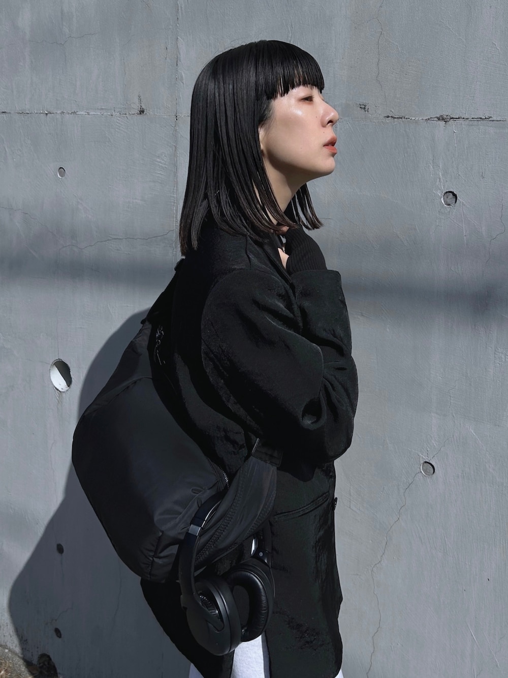 ブラック系のテーラードジャケット、ブラック系のショルダーバッグ、グレー系のスウェットパンツを着用したレディースの春コーディネートの2枚目の写真