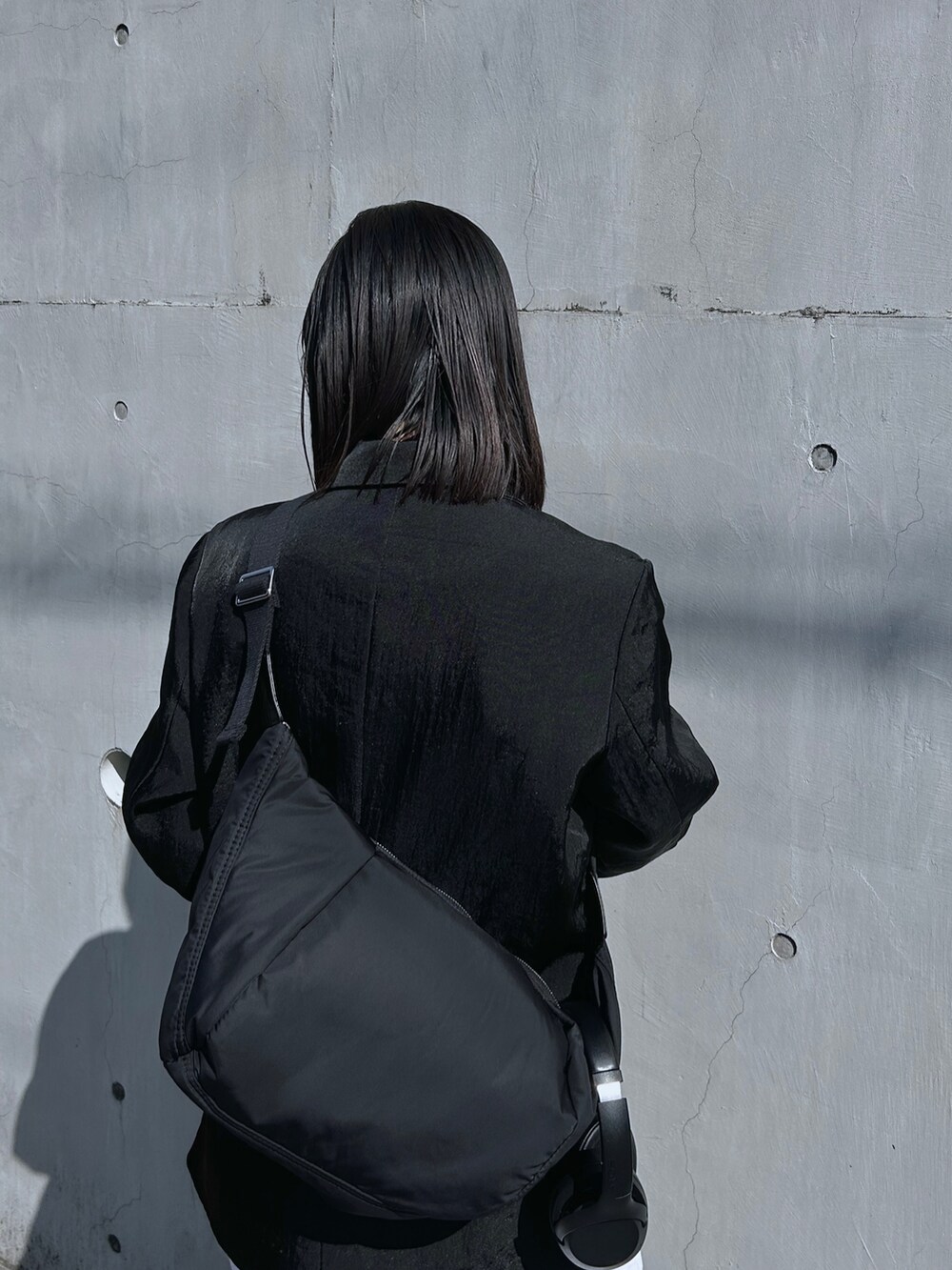 ブラック系のテーラードジャケット、ブラック系のショルダーバッグ、グレー系のスウェットパンツを着用したレディースの春コーディネートの4枚目の写真