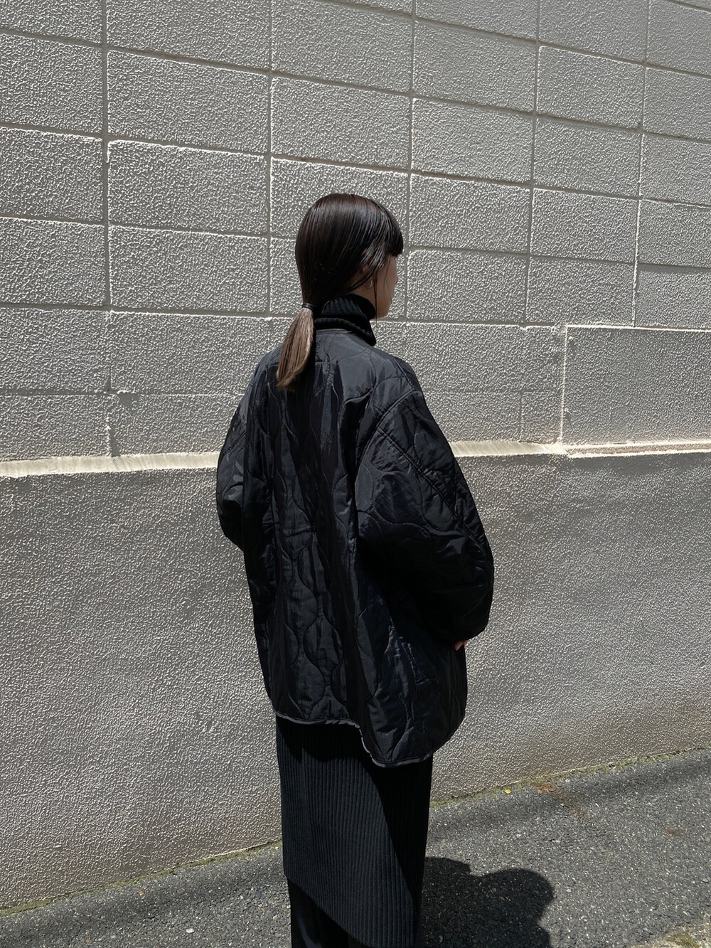 ブラック系のニット/セーター、グレー系のスニーカー、ブラック系のスカートを着用したレディースの夏コーディネートの5枚目の写真