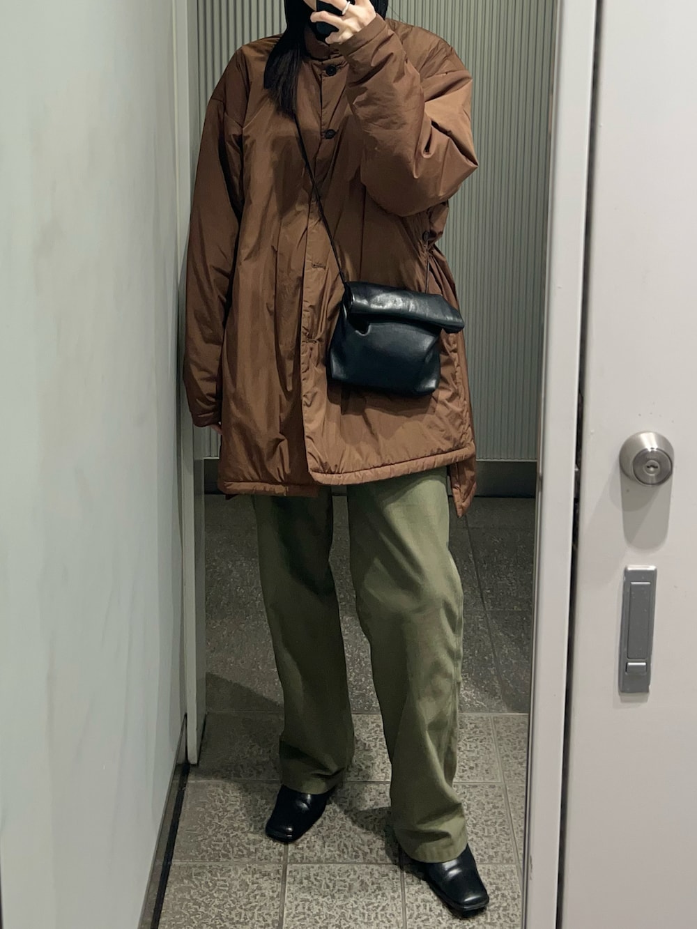 ブラック系のショルダーバッグ、ブラウン系のダウンジャケット/コート、グリーン系のパンツを着用したレディースの冬コーディネートの2枚目の写真