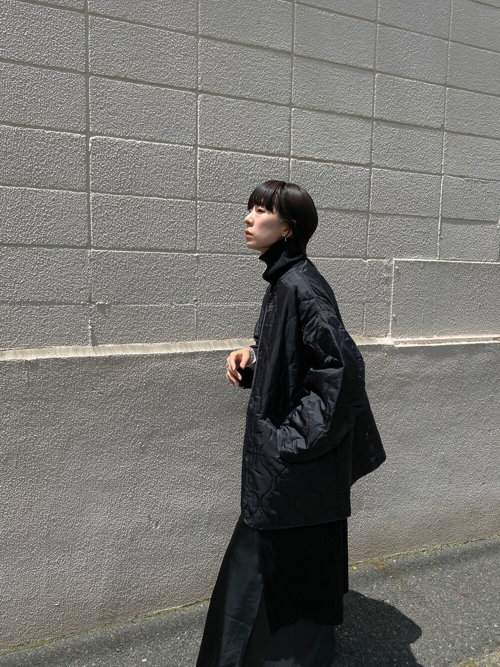 ブラック系のニット/セーター、グレー系のスニーカー、ブラック系のスカートを着用したレディースの夏コーディネートの2枚目の写真