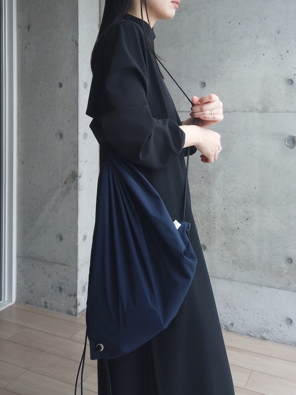 ブラック系のワンピース、ブラック系のモカシン/デッキシューズ、ブルー系のバックパック/リュックを着用したレディースの春コーディネートの2枚目の写真