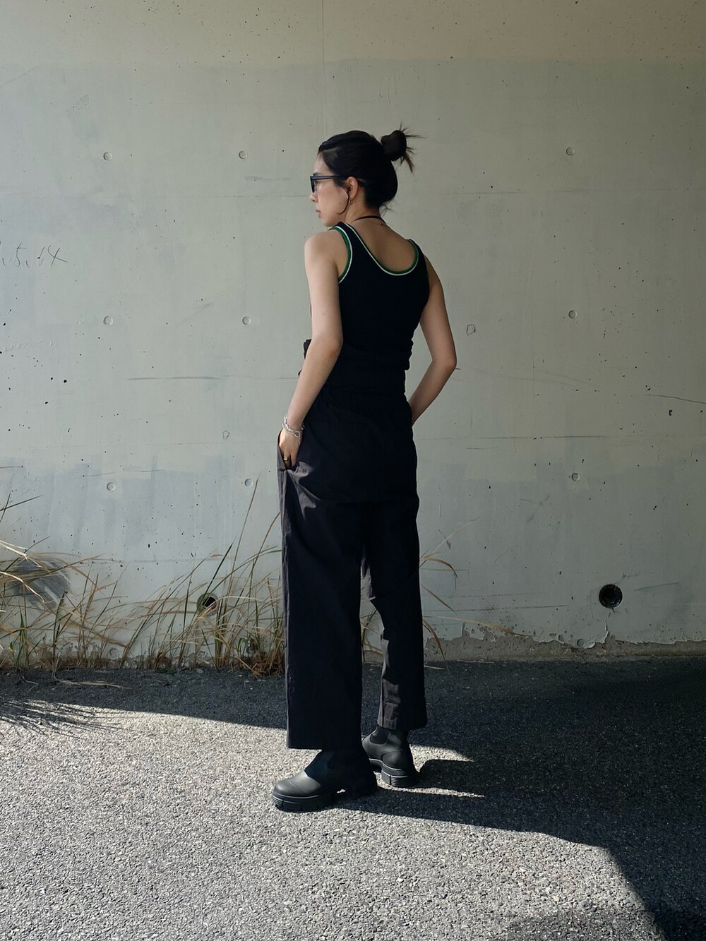 ブラック系のつなぎ/オールインワン、ブラック系のタンクトップ、ブラック系のブーツを着用したレディースの春コーディネートの2枚目の写真