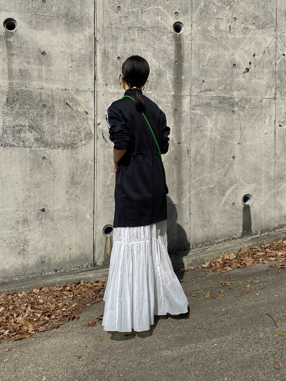 ブラック系のジャージ、ホワイト系のスカート、ブラック系のレインシューズを着用したレディースの春コーディネートの2枚目の写真
