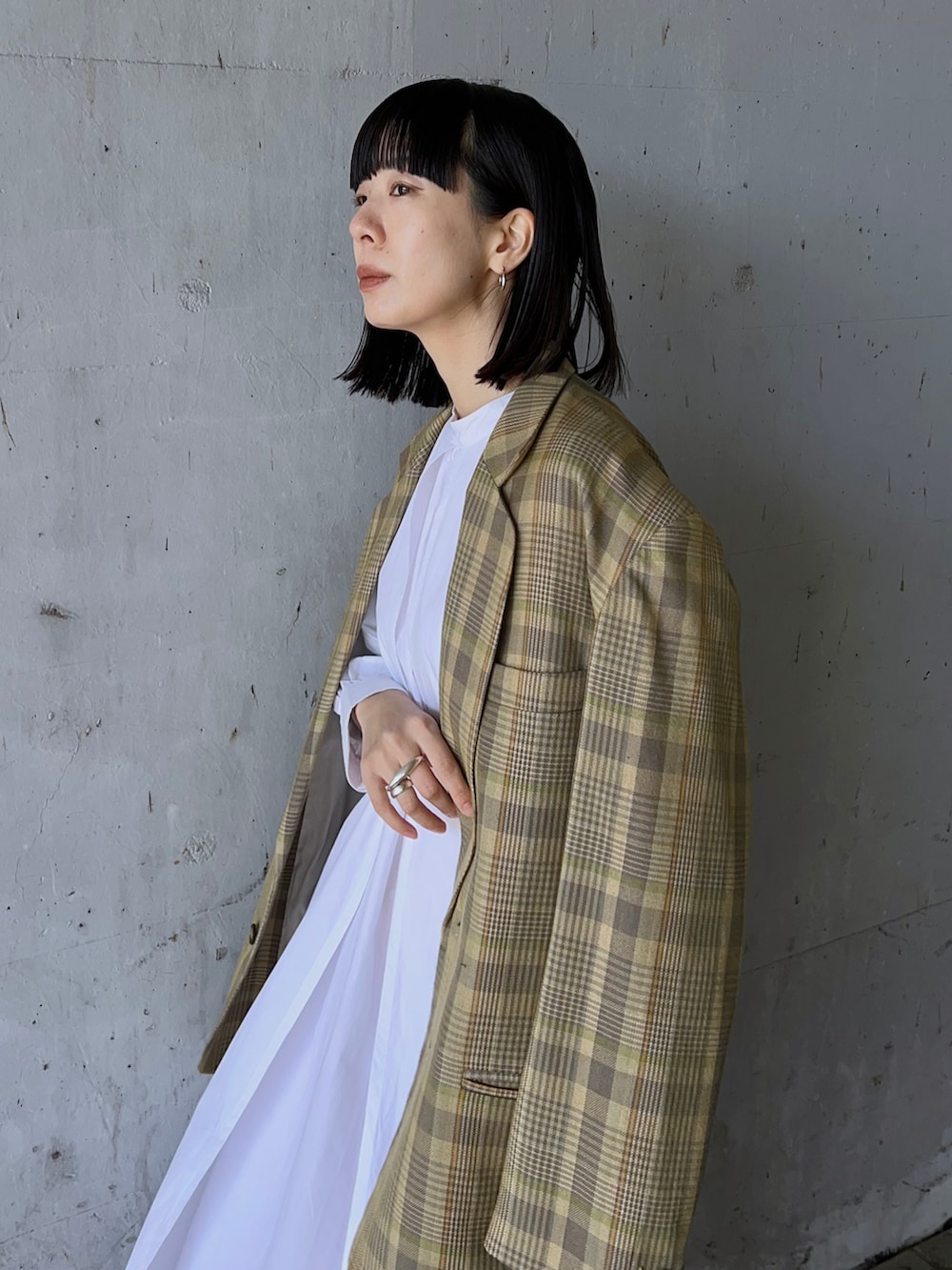 イエロー系のテーラードジャケット、ホワイト系のワンピースを着用したレディースの冬コーディネートの3枚目の写真