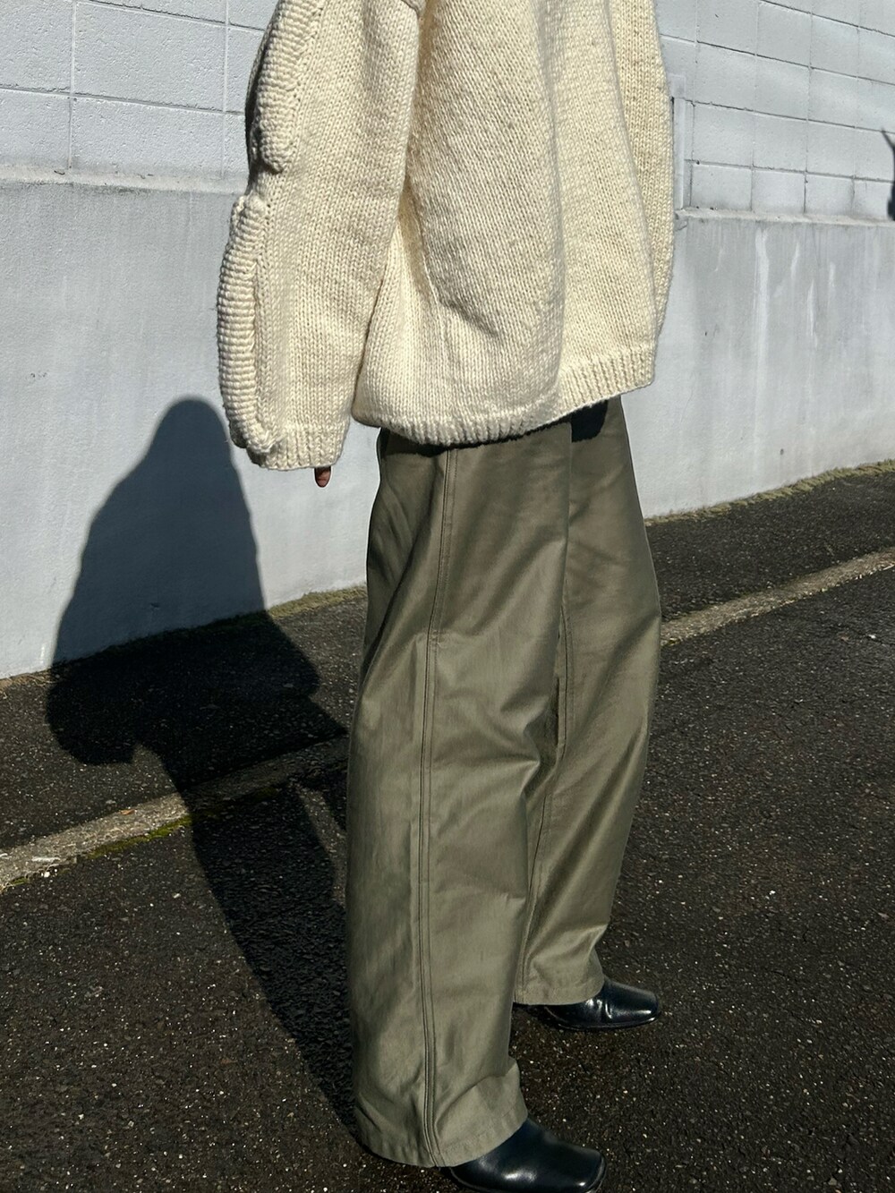 ホワイト系のニット/セーター、グリーン系のパンツ、ブラック系のブーツを着用したレディースの冬コーディネートの3枚目の写真