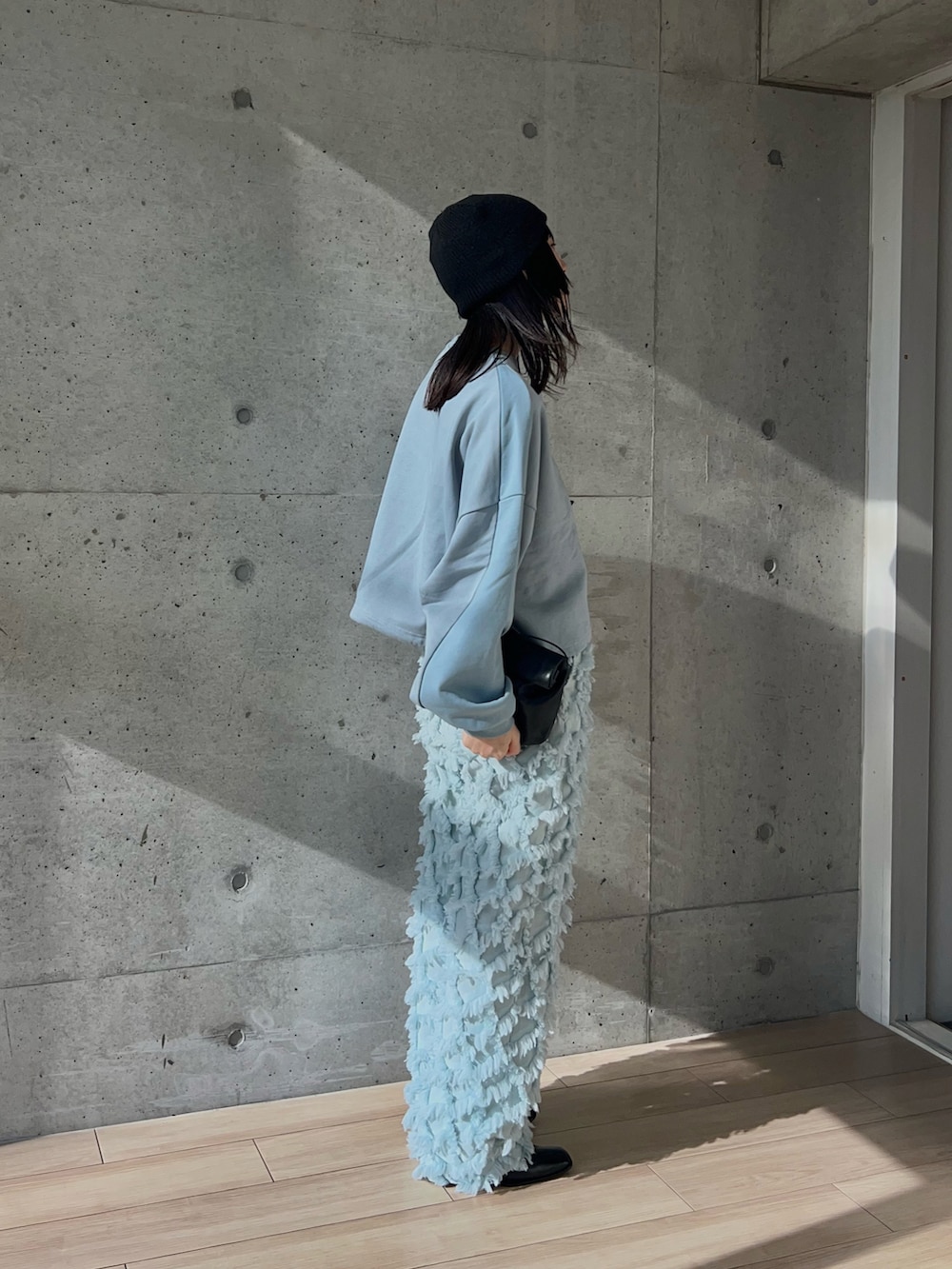 ブルー系のスウェット、ブルー系のパンツ、ブラック系のショルダーバッグを着用したレディースの秋コーディネートの2枚目の写真