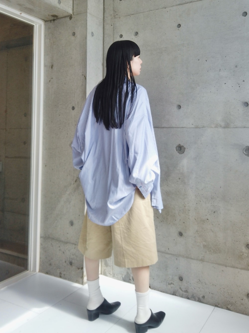 ホワイト系のタンクトップ、ベージュ系のチノパンツ、ブラック系のスリッポンを着用したレディースの春コーディネートの3枚目の写真