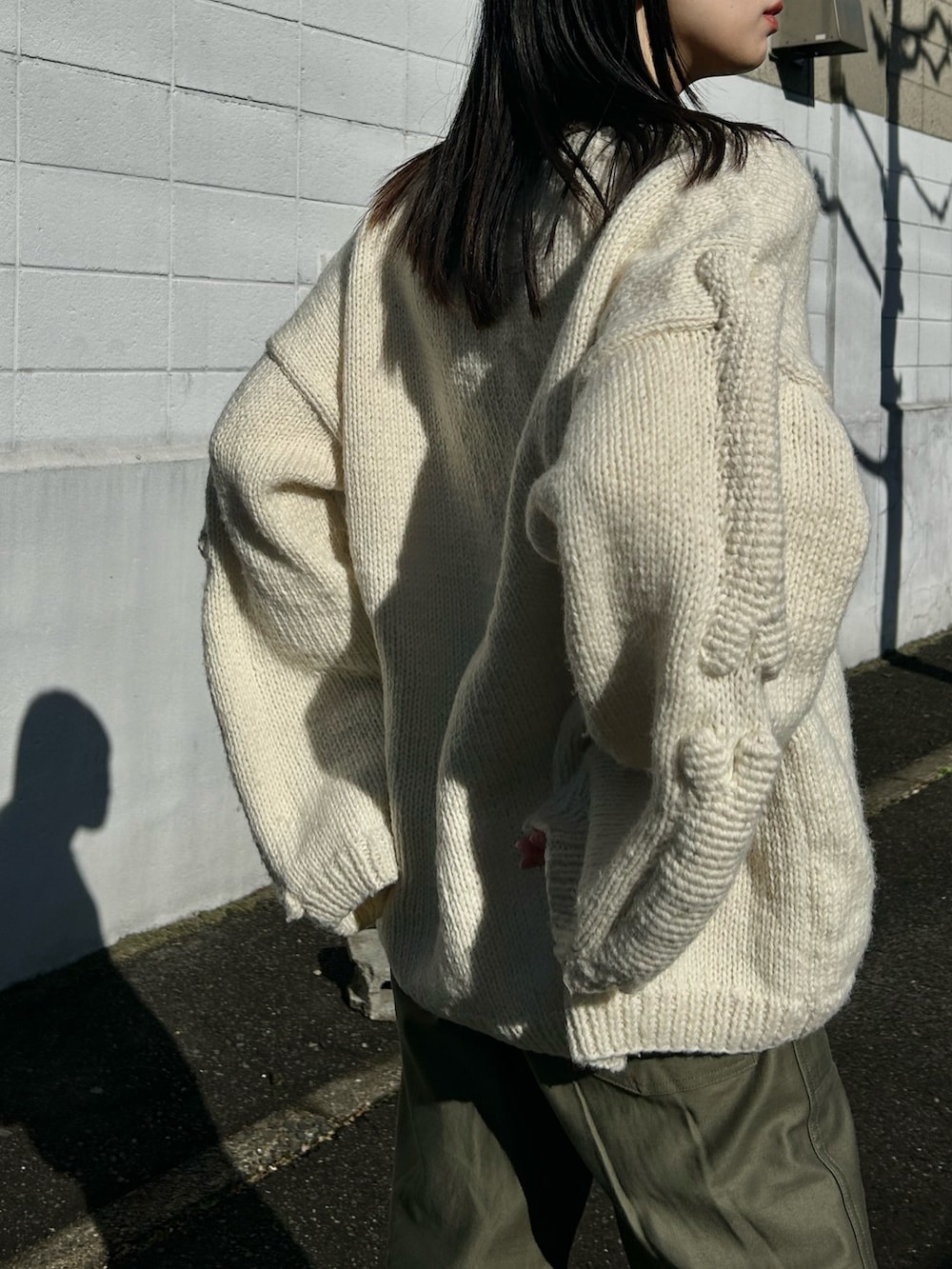 ホワイト系のニット/セーター、グリーン系のパンツ、ブラック系のブーツを着用したレディースの冬コーディネートの2枚目の写真