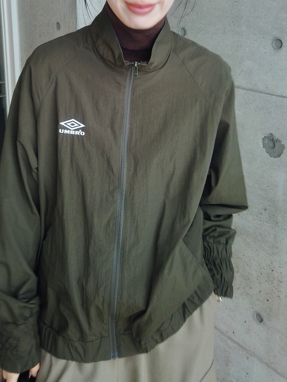 グリーン系のその他アウター、ブラウン系のニット/セーター、ブラック系のハンドバッグを着用したレディースの冬コーディネートの3枚目の写真