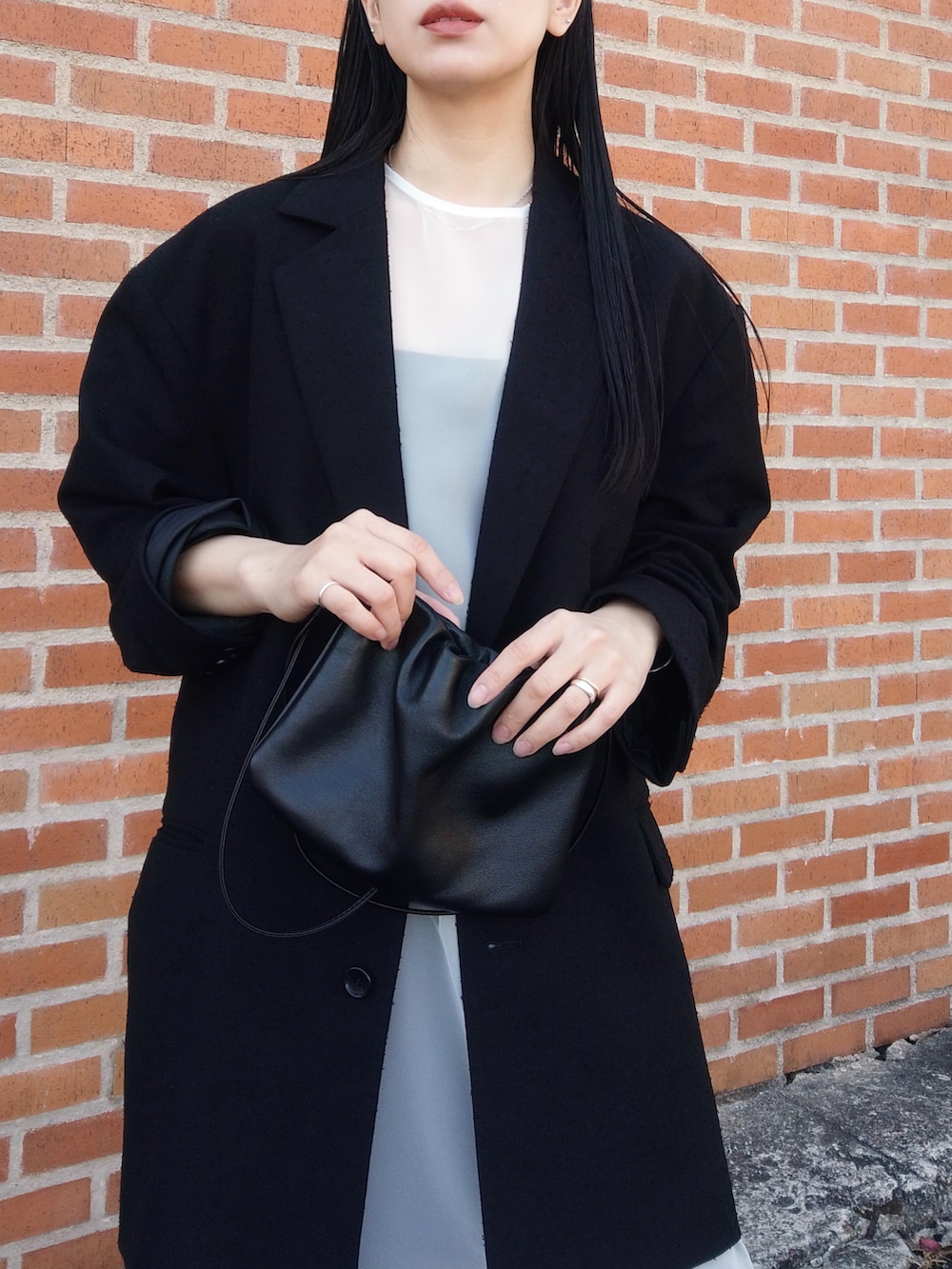 ブラック系のデニムパンツ、ブラック系のテーラードジャケット、ホワイト系のワンピースを着用したレディースの春コーディネートの3枚目の写真