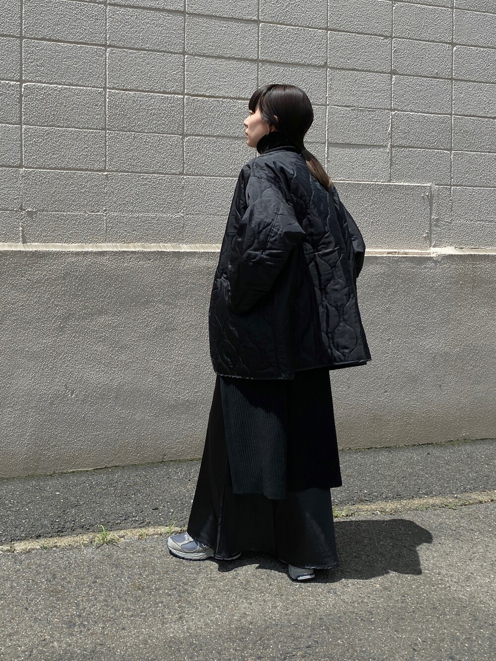 ブラック系のニット/セーター、グレー系のスニーカー、ブラック系のスカートを着用したレディースの夏コーディネートの3枚目の写真