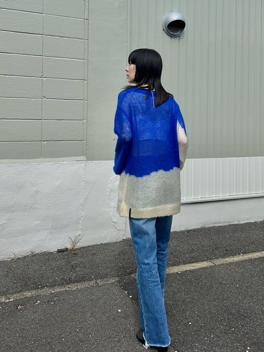 ブルー系のニット/セーター、ブルー系のデニムパンツ、ベージュ系のファンデーションを着用したレディースの秋コーディネートの4枚目の写真