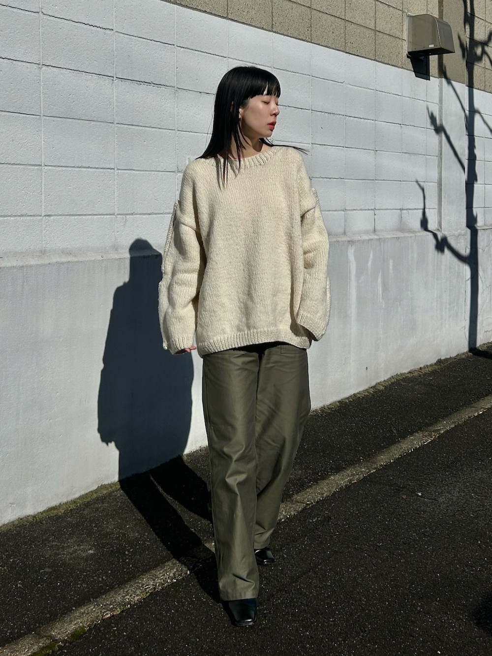 ホワイト系のニット/セーター、グリーン系のパンツ、ブラック系のブーツを着用したレディースの冬コーディネートの4枚目の写真