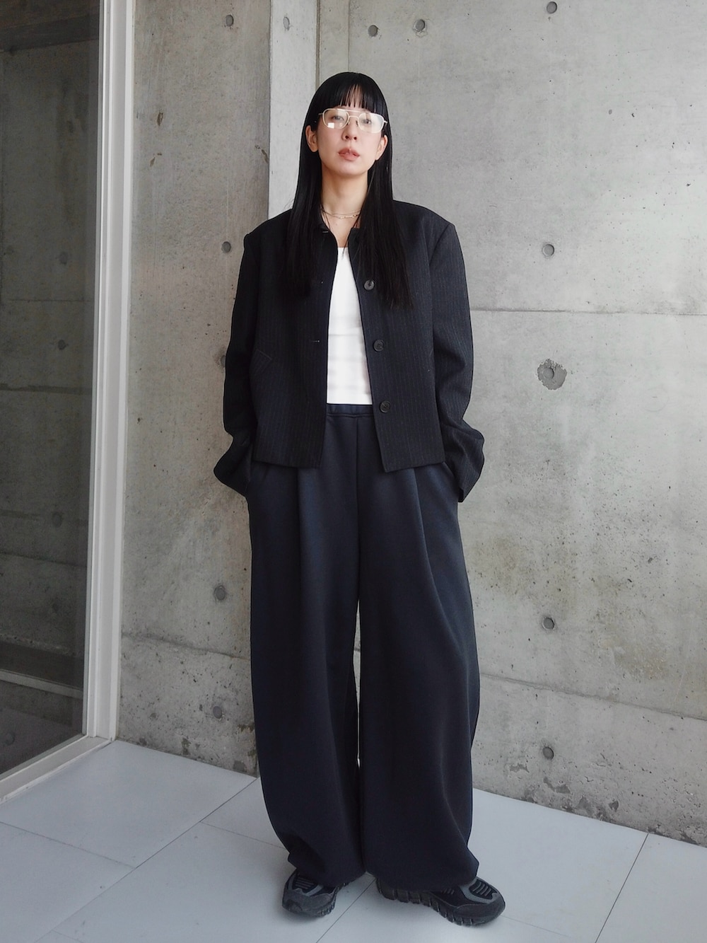 ブラック系のその他アウター、ブラック系のスニーカー、ホワイト系のTシャツ/カットソーを着用したレディースの冬コーディネートの2枚目の写真