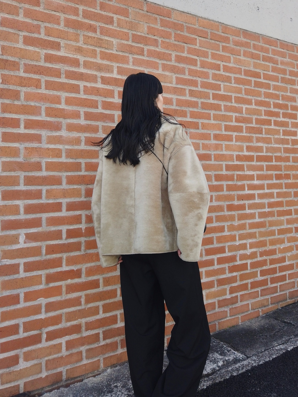 ブラック系のスラックス、ベージュ系のブルゾン、ブラック系のコインケースを着用したレディースの冬コーディネートの3枚目の写真