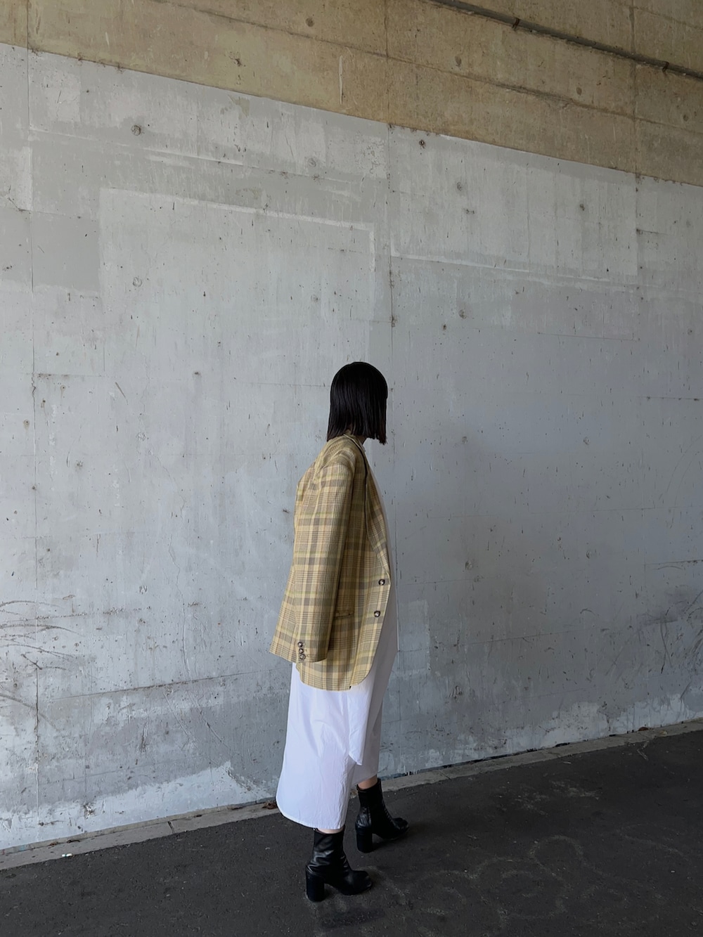 イエロー系のテーラードジャケット、ホワイト系のワンピースを着用したレディースの冬コーディネートの2枚目の写真