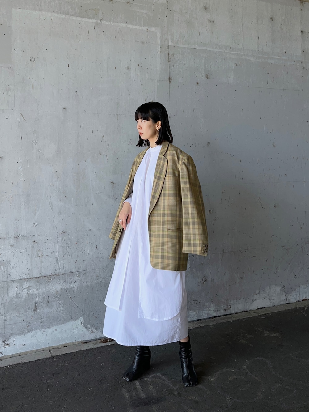 イエロー系のテーラードジャケット、ホワイト系のワンピースを着用したレディースの冬コーディネートの4枚目の写真