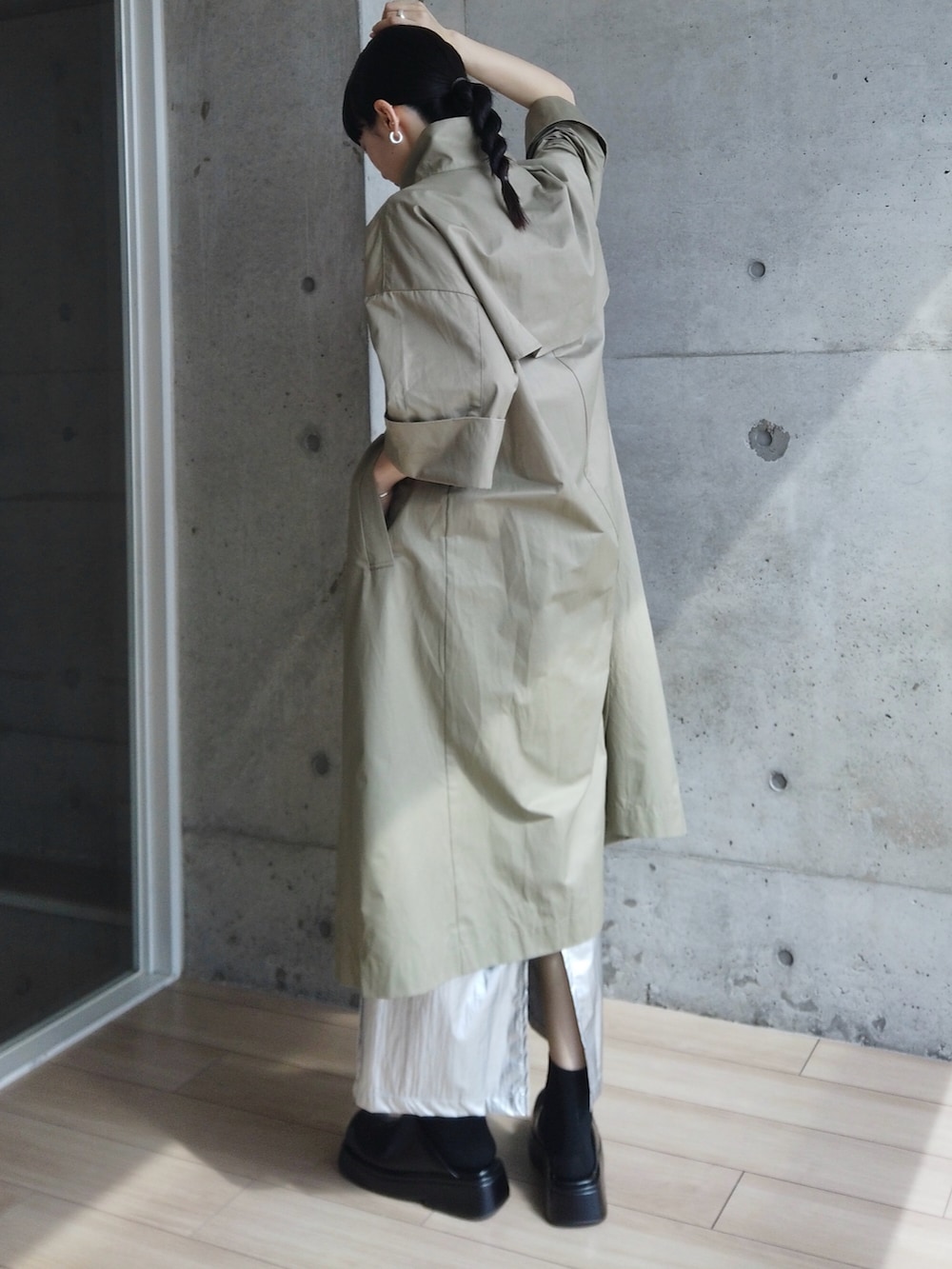 シルバー系のスカート、グリーン系のトレンチコート、ブラック系のシューズを着用したレディースの春コーディネートの2枚目の写真