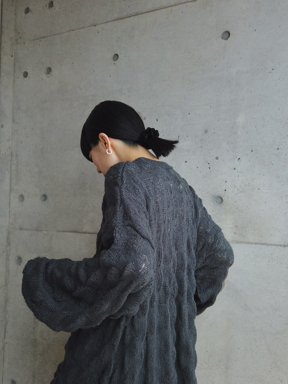 グレー系のニット/セーター、ブラック系のスカート、シルバー系のピアス（両耳用）を着用したレディースの秋コーディネートの3枚目の写真