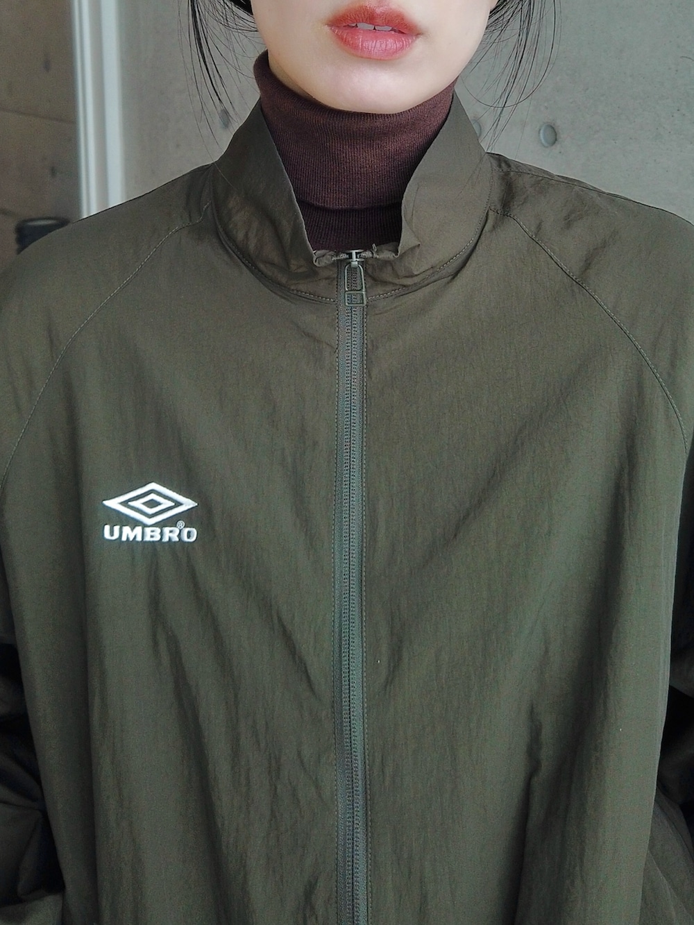 グリーン系のその他アウター、ブラウン系のニット/セーター、ブラック系のハンドバッグを着用したレディースの冬コーディネートの2枚目の写真