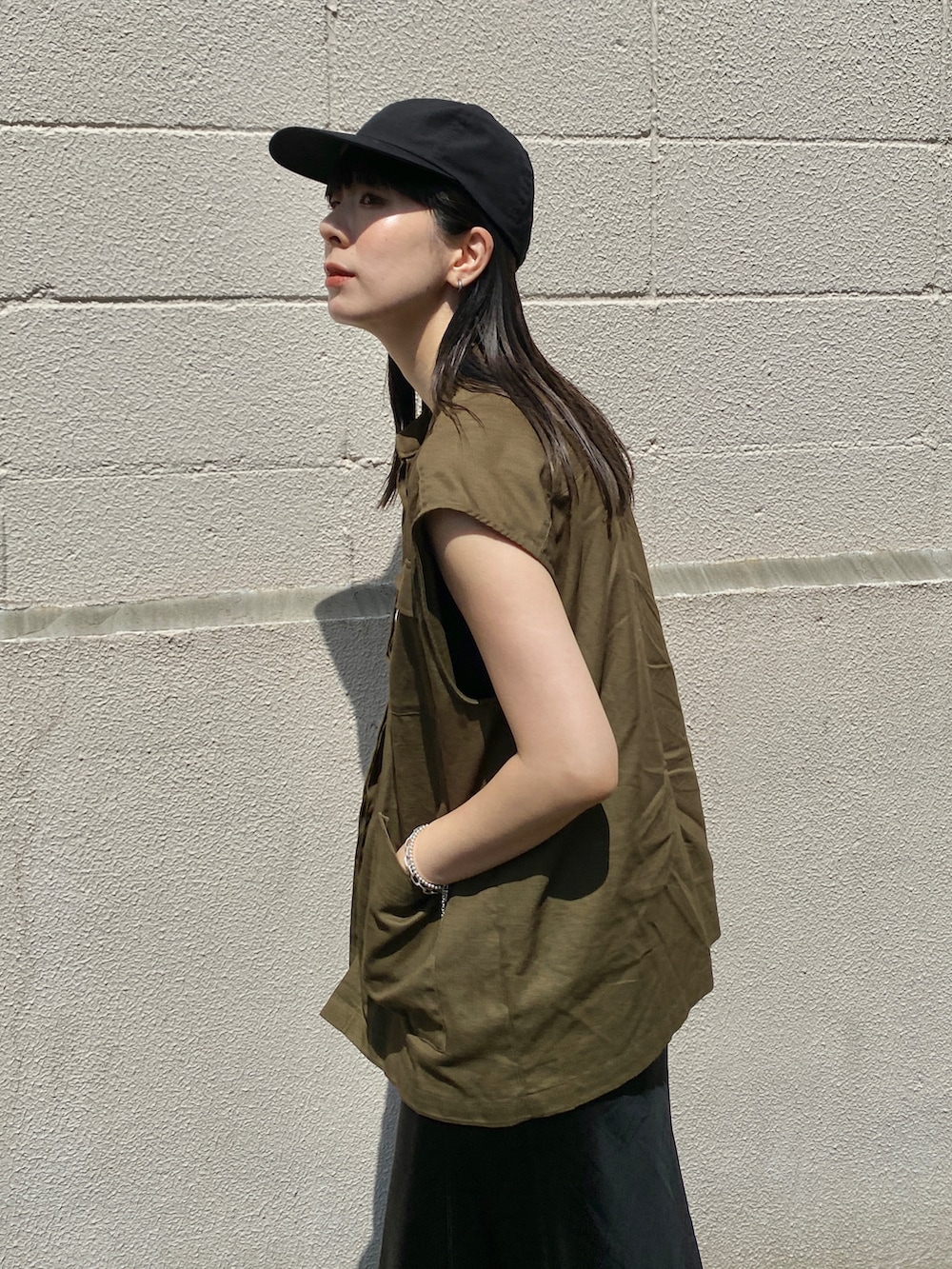 グリーン系のベスト、ブラック系のスカート、ブラック系のサンダルを着用したレディースの夏コーディネートの3枚目の写真