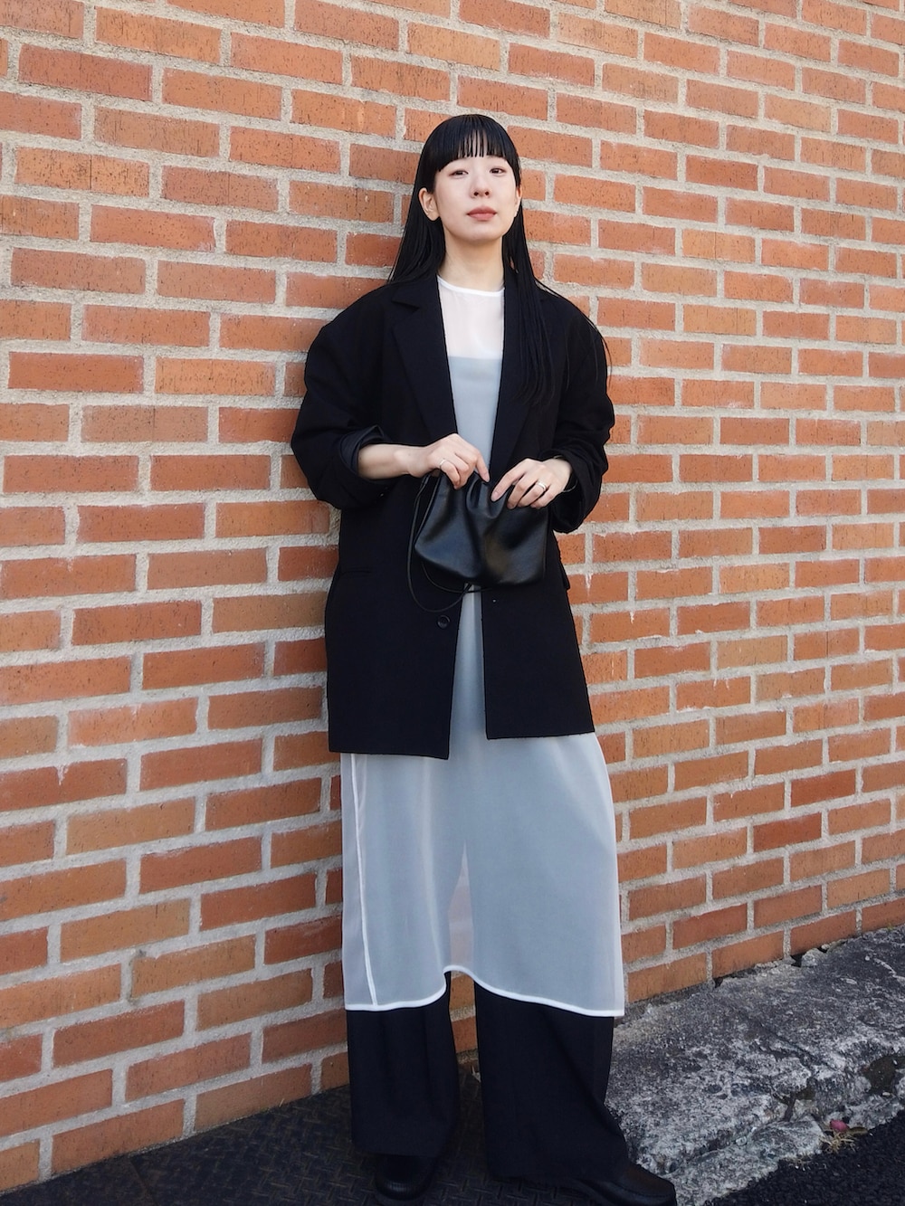 ブラック系のデニムパンツ、ブラック系のテーラードジャケット、ホワイト系のワンピースを着用したレディースの春コーディネートの2枚目の写真