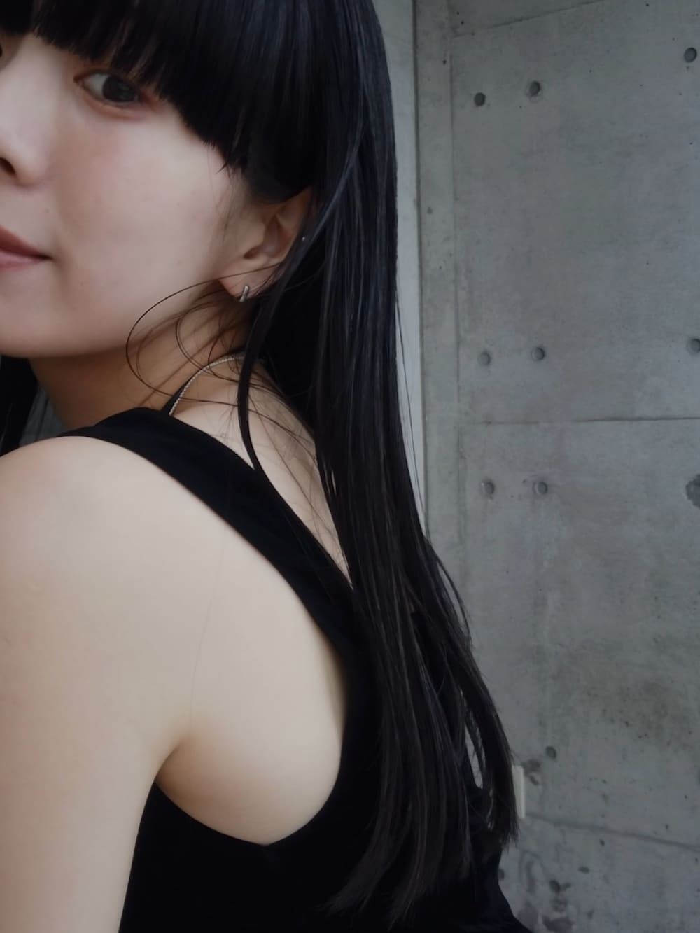 ブルー系のデニムスカート、ブルー系のデニムジャケット、ブラック系のタンクトップを着用したレディースの春コーディネートの2枚目の写真