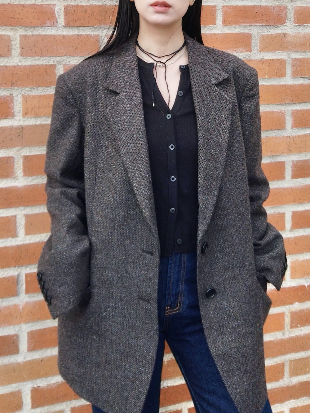 ブルー系のデニムパンツ、ブラック系のカーディガン/ボレロ、ブラウン系のテーラードジャケットを着用したレディースの春コーディネートの2枚目の写真