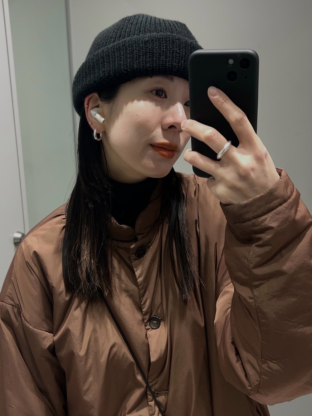 ブラック系のショルダーバッグ、ブラウン系のダウンジャケット/コート、グリーン系のパンツを着用したレディースの冬コーディネートの3枚目の写真