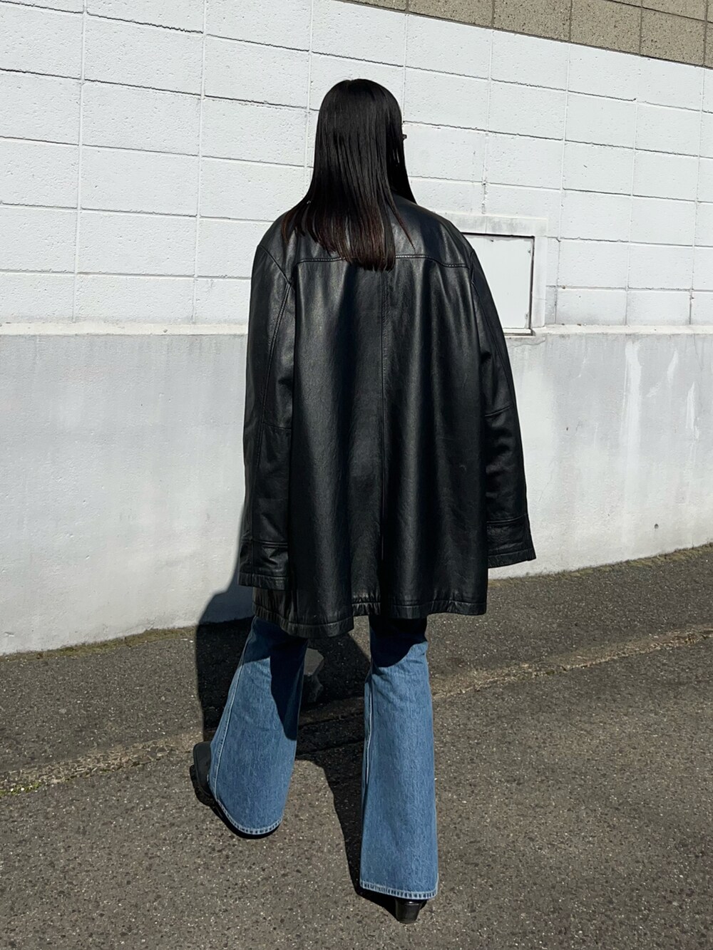 ブラック系のジャケット/アウター、ホワイト系のニット/セーター、ブルー系のデニムパンツを着用したレディースの冬コーディネートの2枚目の写真