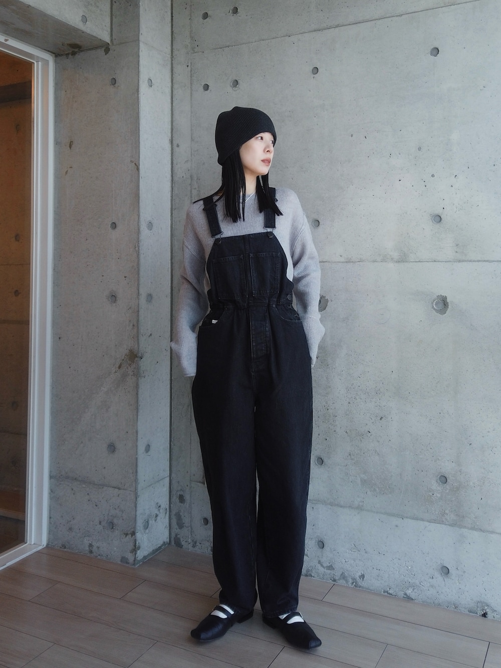 ブルー系のニット/セーター、ブラック系のオールインワン・サロペット、グレー系のニットキャップ/ビーニーを着用したレディースの春コーディネートの2枚目の写真