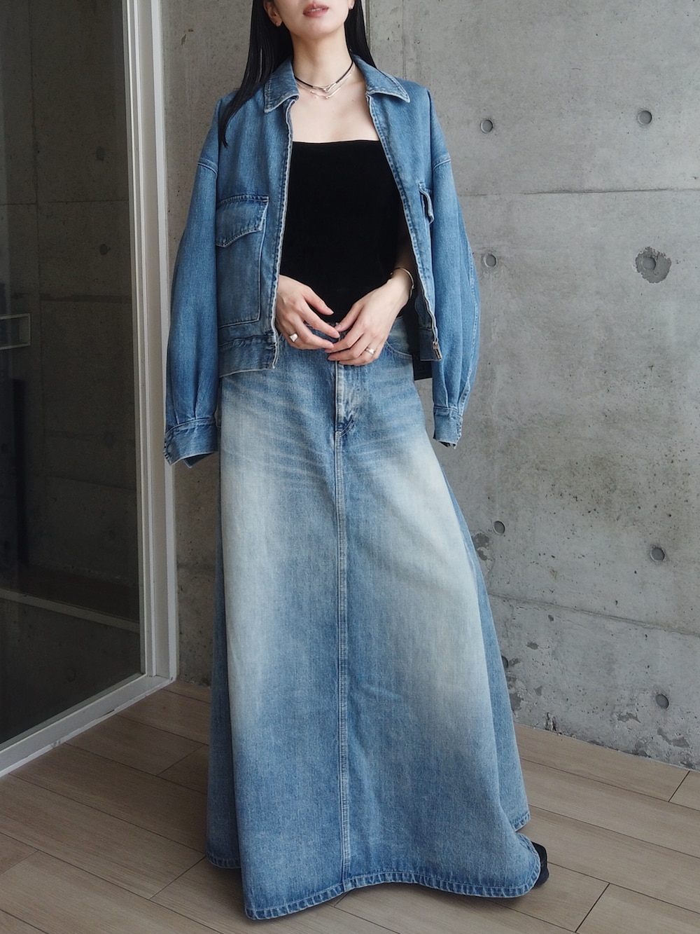 ブルー系のデニムスカート、ブルー系のデニムジャケット、ブラック系のタンクトップを着用したレディースの春コーディネートの3枚目の写真