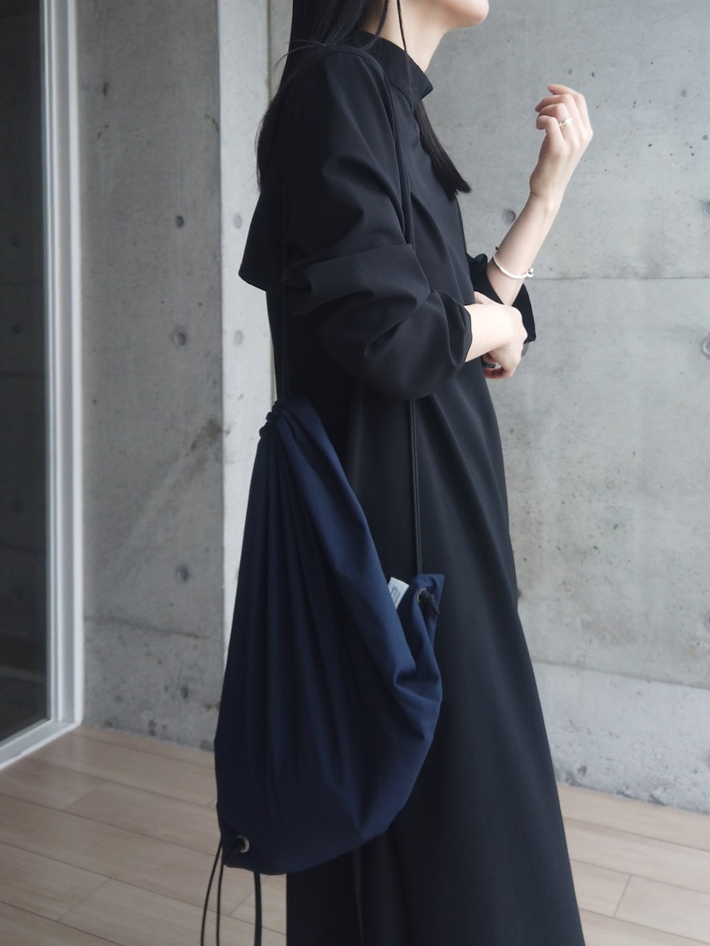 ブラック系のワンピース、ブラック系のモカシン/デッキシューズ、ブルー系のバックパック/リュックを着用したレディースの春コーディネートの3枚目の写真