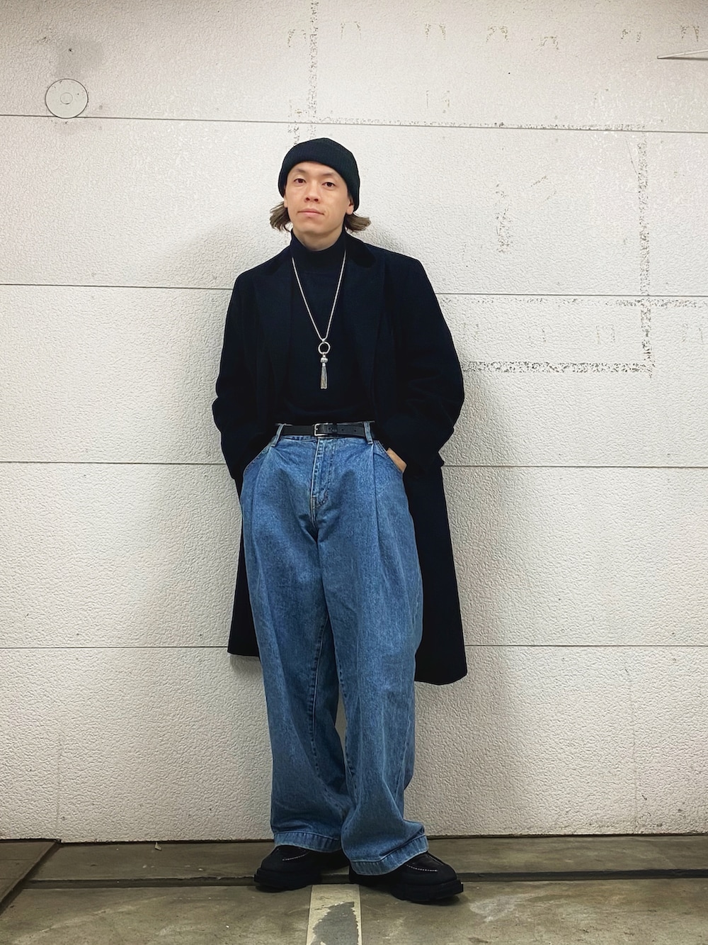 ブラック系のチェスターコート、ブルー系のデニムパンツ、ブラック系のローファーを着用したメンズの春コーディネートの2枚目の写真