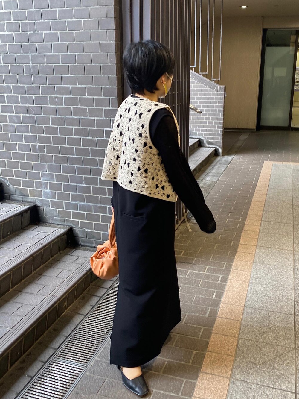 ブラック系のワンピース、ブラック系のニット/セーター、ベージュ系のベストを着用したレディースの春コーディネートの5枚目の写真