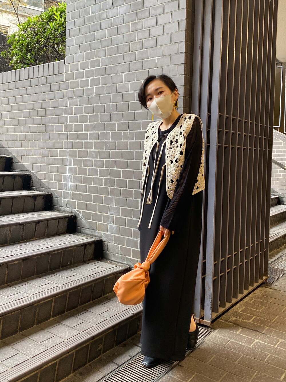 ブラック系のワンピース、ブラック系のニット/セーター、ベージュ系のベストを着用したレディースの春コーディネートの4枚目の写真