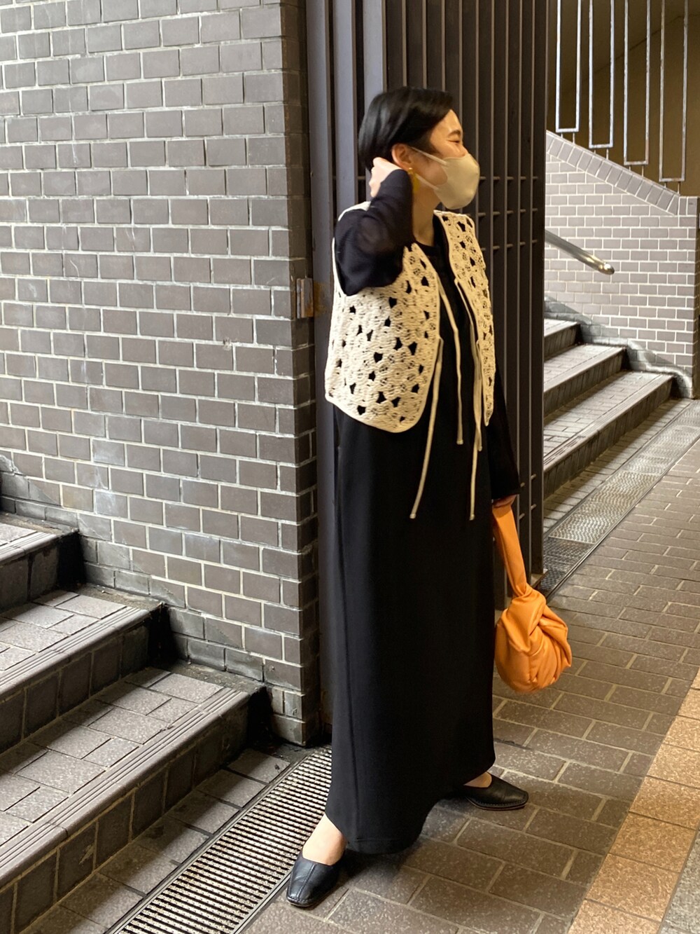 ブラック系のワンピース、ブラック系のニット/セーター、ベージュ系のベストを着用したレディースの春コーディネートの3枚目の写真