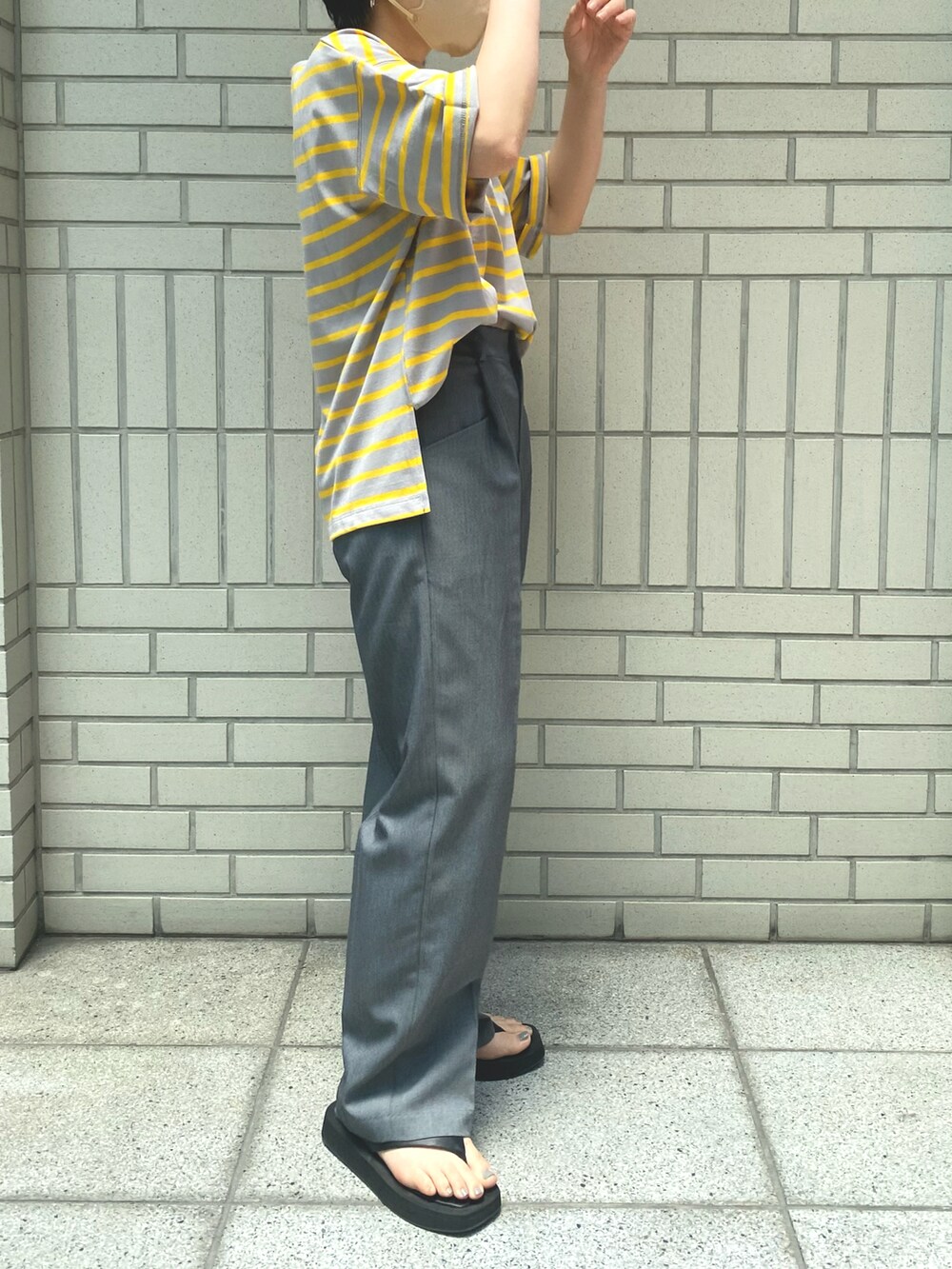グレー系のスラックス、イエロー系のTシャツ/カットソー、ブラック系のサンダルを着用したレディースの夏コーディネートの2枚目の写真