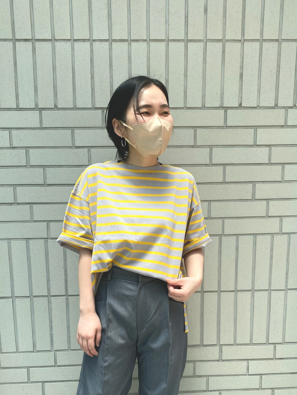 グレー系のスラックス、イエロー系のTシャツ/カットソー、ブラック系のサンダルを着用したレディースの夏コーディネートの5枚目の写真