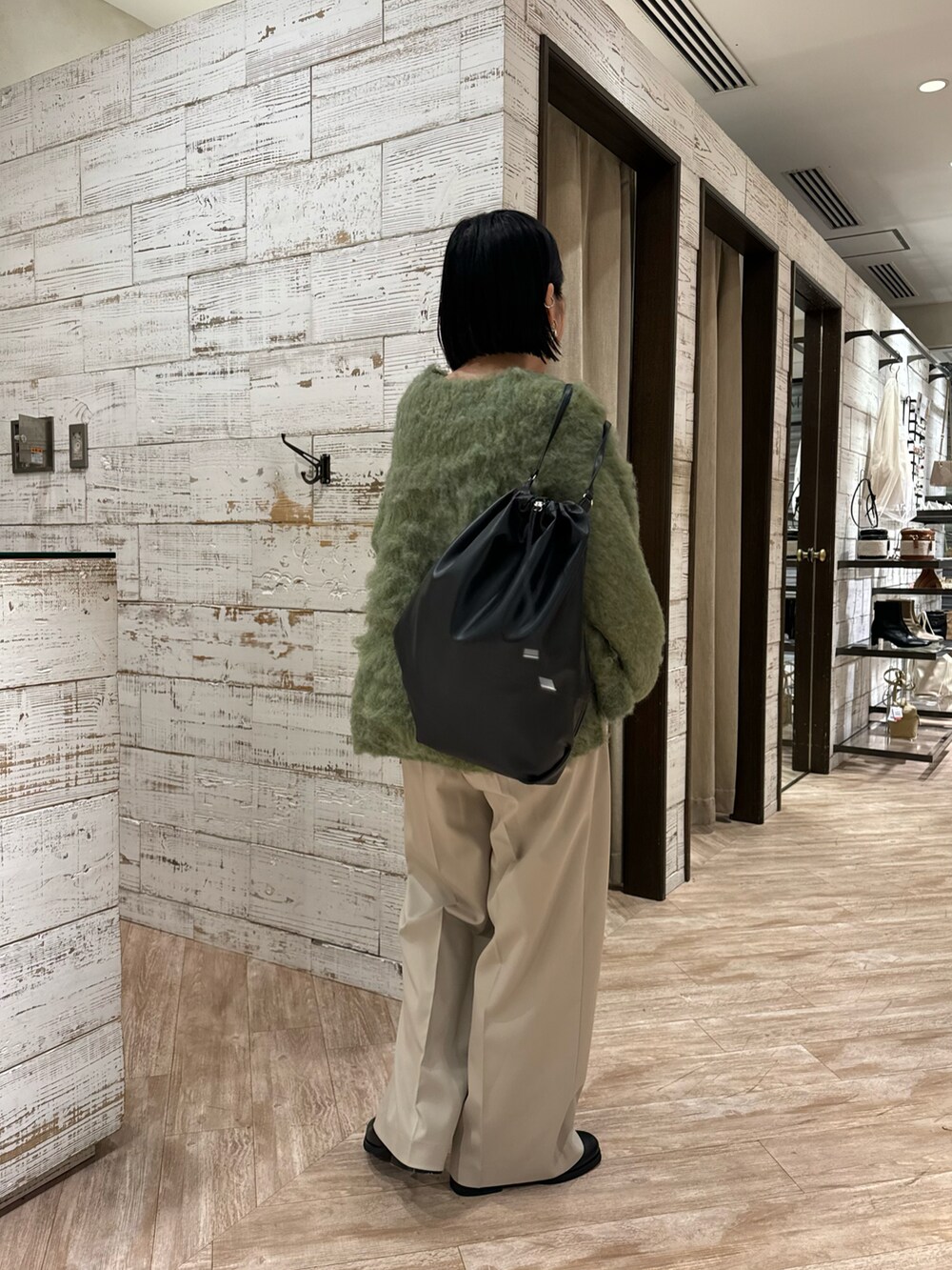 グリーン系のニット/セーター、ベージュ系のパンツ、ブラック系のバックパック/リュックを着用したレディースの冬コーディネートの3枚目の写真