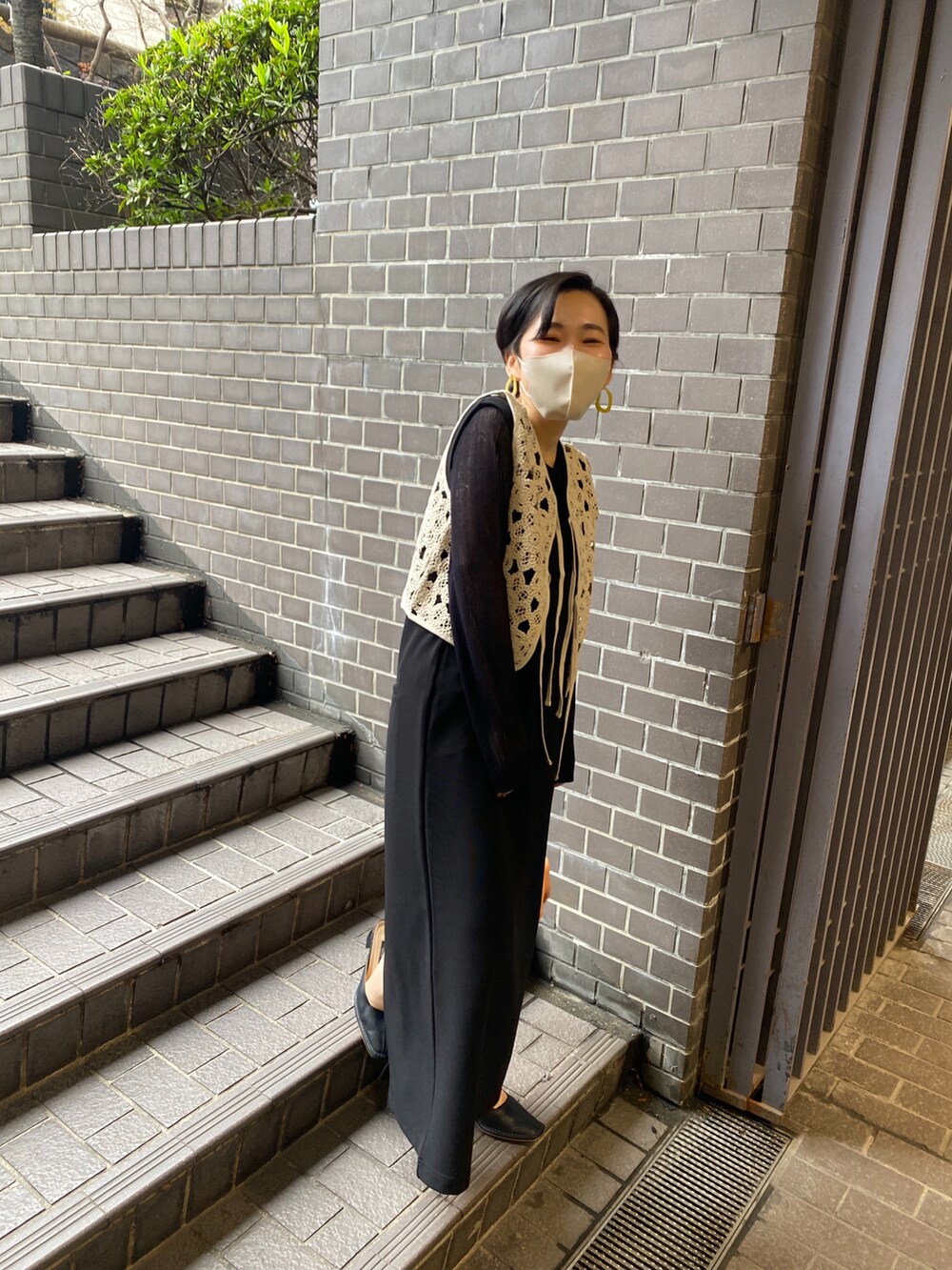 ブラック系のワンピース、ブラック系のニット/セーター、ベージュ系のベストを着用したレディースの春コーディネートの2枚目の写真