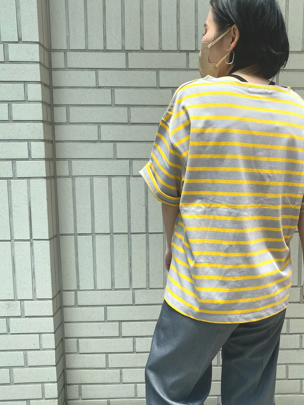 グレー系のスラックス、イエロー系のTシャツ/カットソー、ブラック系のサンダルを着用したレディースの夏コーディネートの4枚目の写真