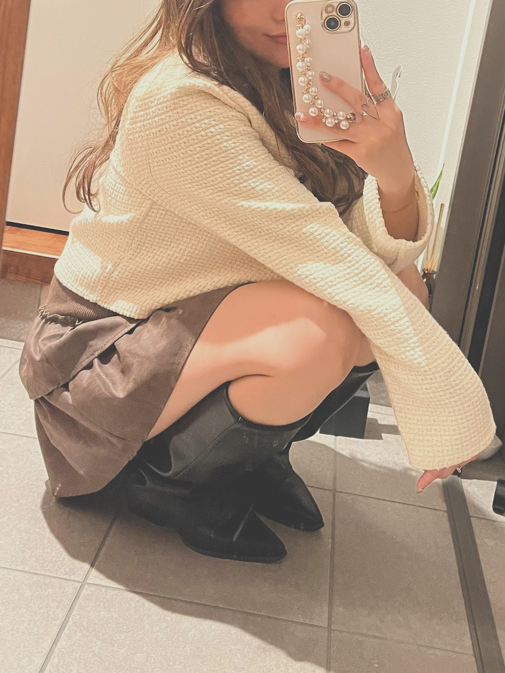 ブラウン系のスカート、ブラック系のブーツを着用したレディースの秋コーディネートの3枚目の写真