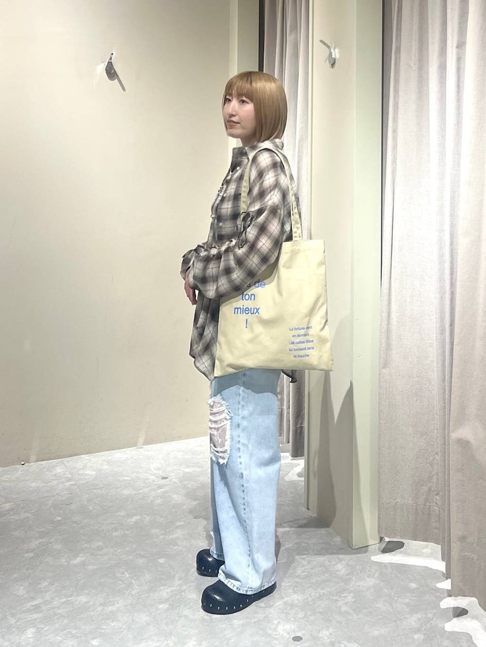 ブルー系のデニムパンツ、ベージュ系のトートバッグ、ブラック系のサンダルを着用したレディースの春コーディネートの2枚目の写真